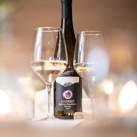 The picture shows a bottle of wine and two style glasses. The glasses contain the white wine.