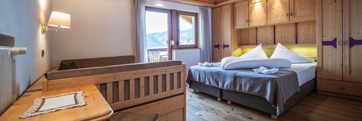 teiser stern Villnöss Eisacktal Südtirol – Zimmer für Paare und Familien – Urlauben in Südtirol Das Bild zeigt ein liebevoll germachtes kuscheliges Bett im Vollholz-Zimmer des teiser stern.