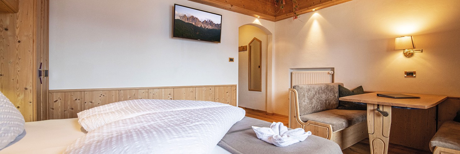 teiser stern Villnöss Eisacktal Südtirol – Zimmer für Paare und Familien – Urlauben im Eisacktal Das Bild zeigt ein liebevoll germachtes kuscheliges Bett im Vollholz-Zimmer des teiser stern.