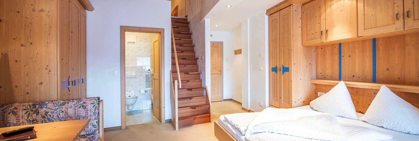 Das Bild zeigt ein liebevoll germachtes kuscheliges Bett im Vollholz-Zimmer des teiser stern.