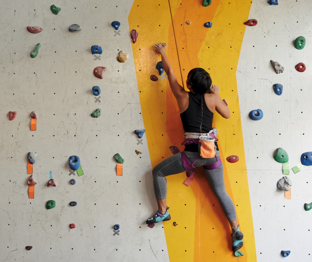 The picture shows a person climbing up the wall in the climbing hall during a holiday in South Tyrol.