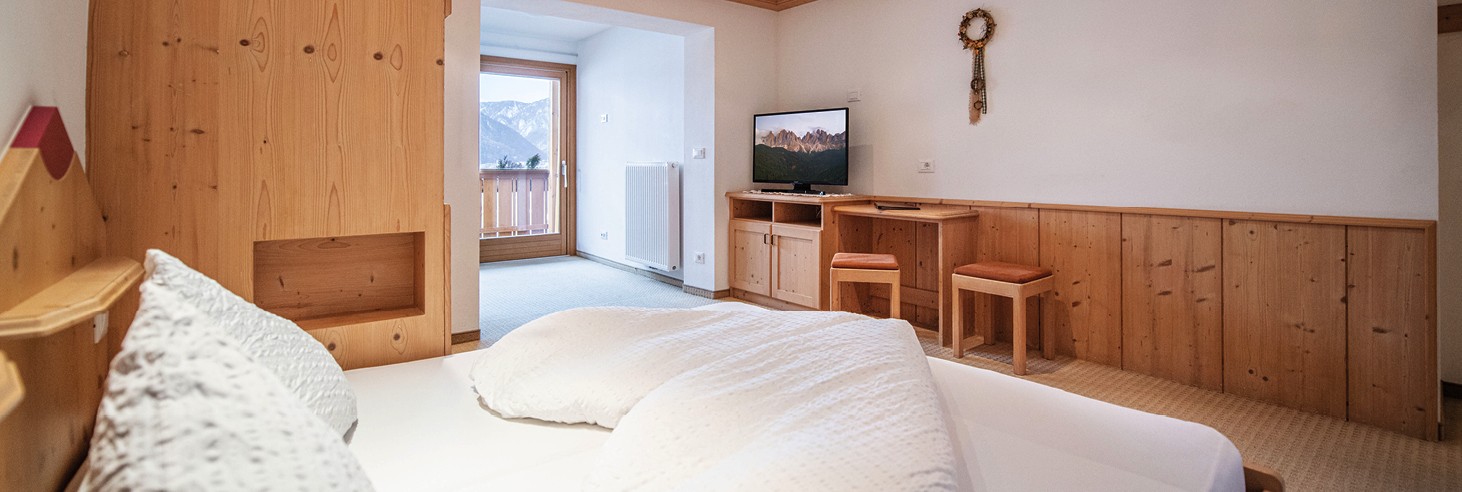 Das Bild zeigt ein liebevoll germachtes kuscheliges Bett im Vollholz-Zimmer des teiser stern.