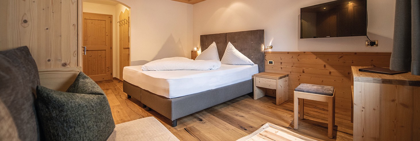 Das Bild zeigt ein liebevoll germachtes kuscheliges Bett im Vollholz-Zimmer des teiser stern.