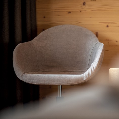 The picture shows a comfortable and modern plain armchair. It stands in a room of the teiser stern.