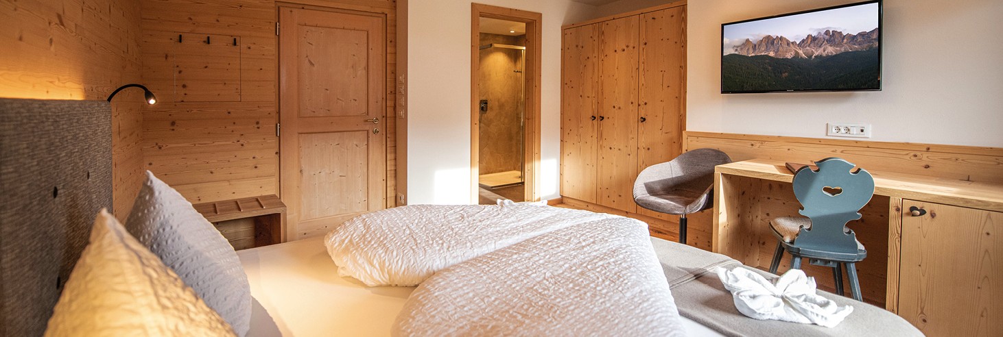 Das Bild zeigt ein liebevoll germachtes kuscheliges Bett im Vollholz-Zimmer des teiser stern.